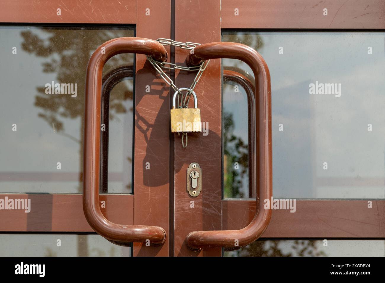 A rustic brown wooden door with a vintage gold padlock and chain, set ...