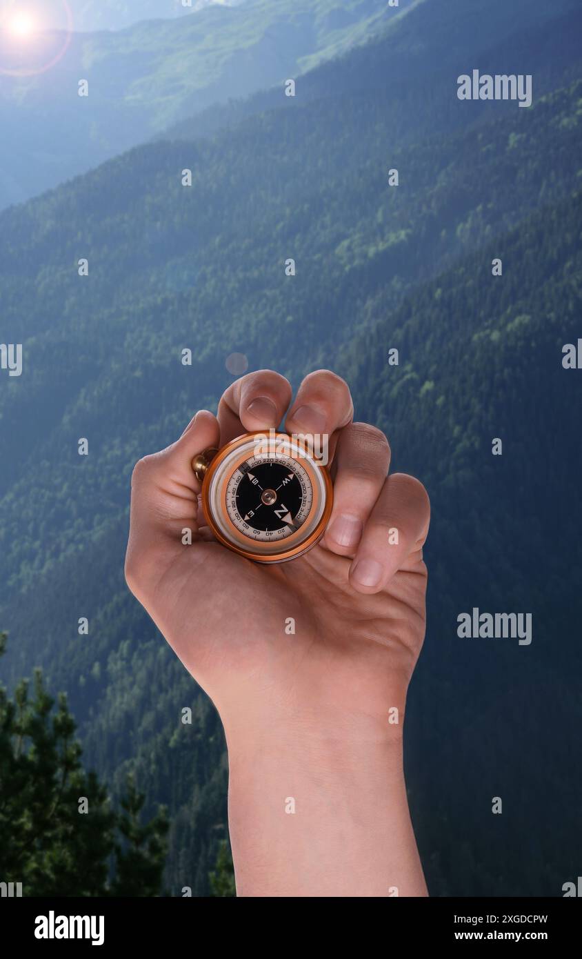 Man using compass in mountains, closeup. Navigational instrument Stock Photo
