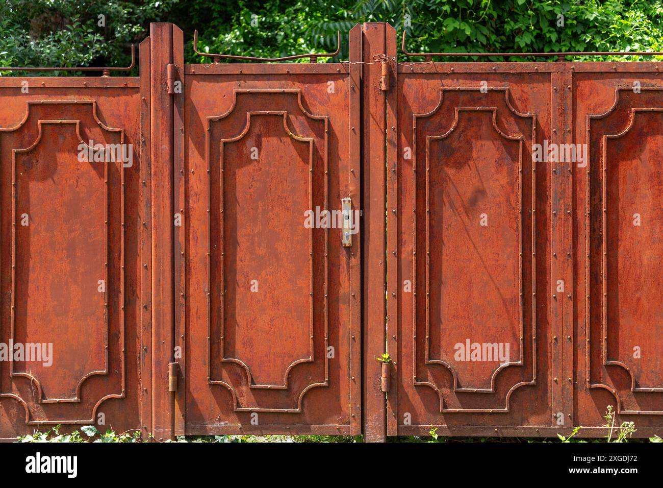 Neglected garden door with rusty metallic panels, wide rural fence gate Stock Photo