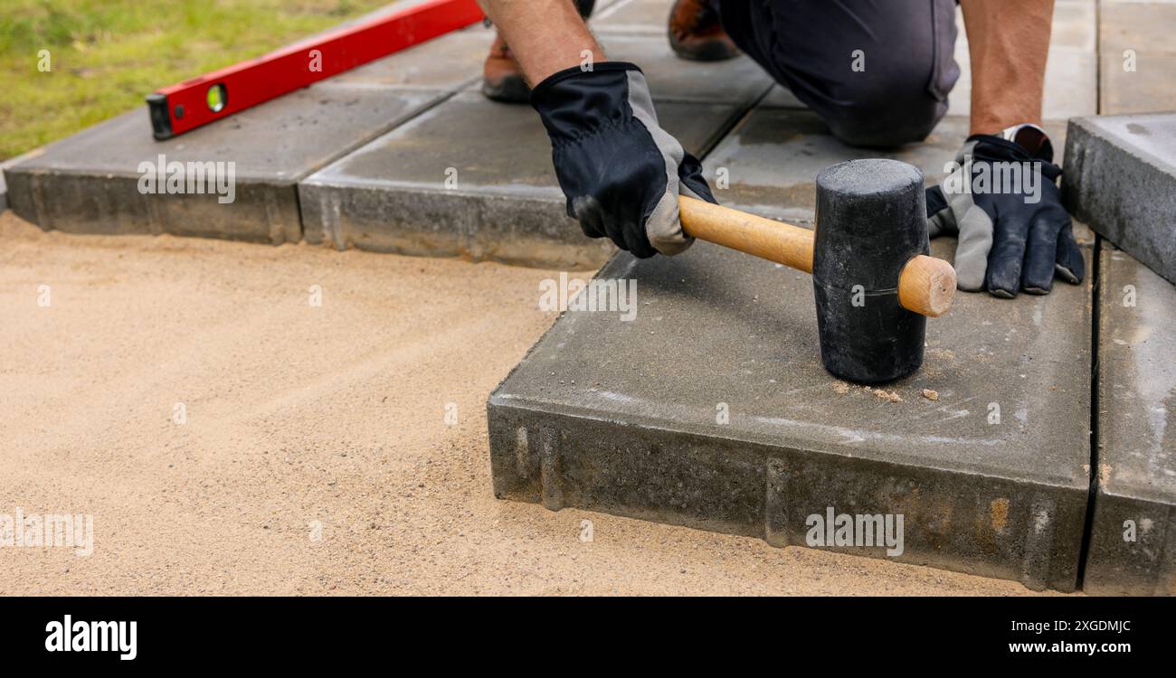 man laying concrete paving slabs for patio Stock Photo
