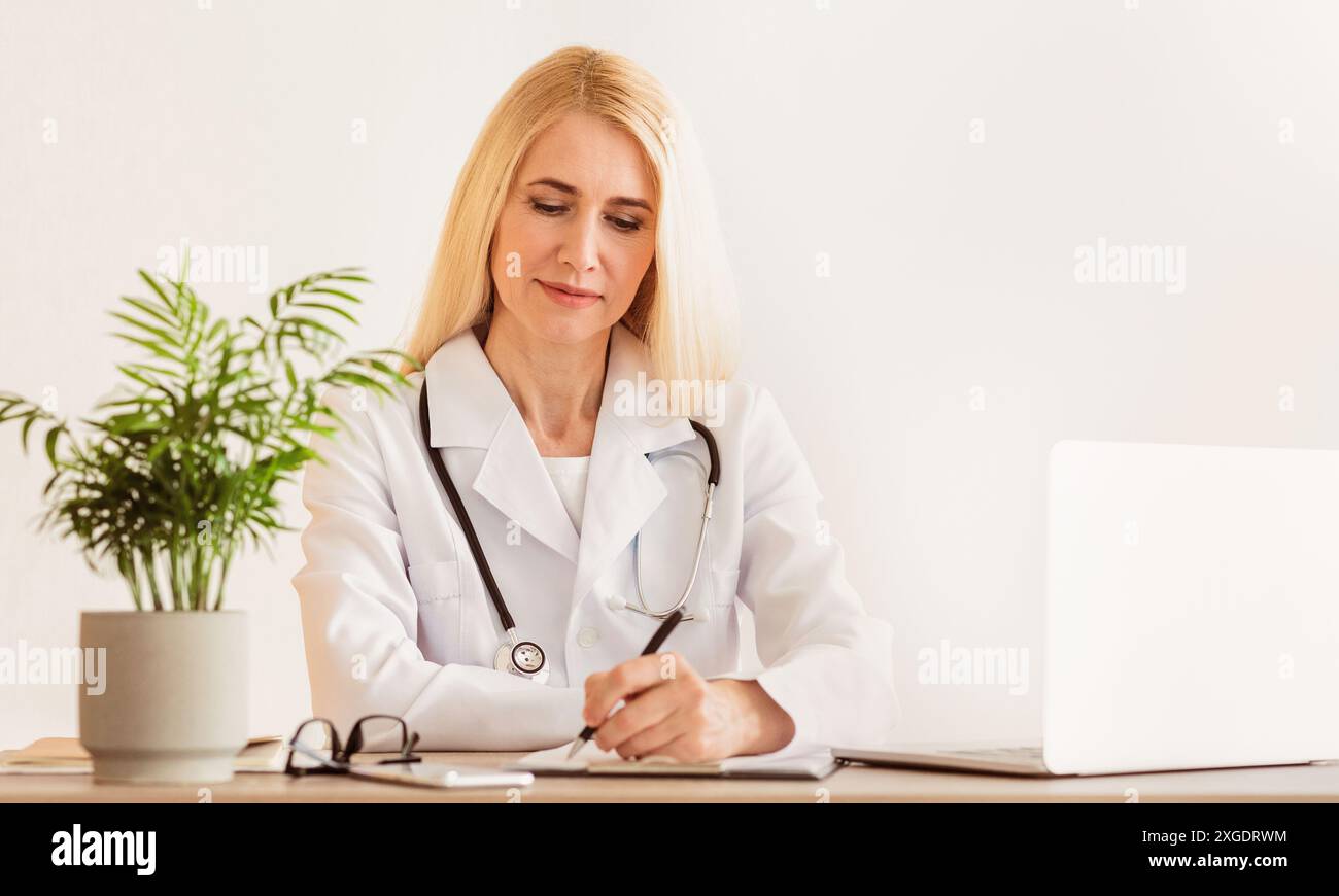Female Doctor Writing Notes in Office Stock Photo - Alamy