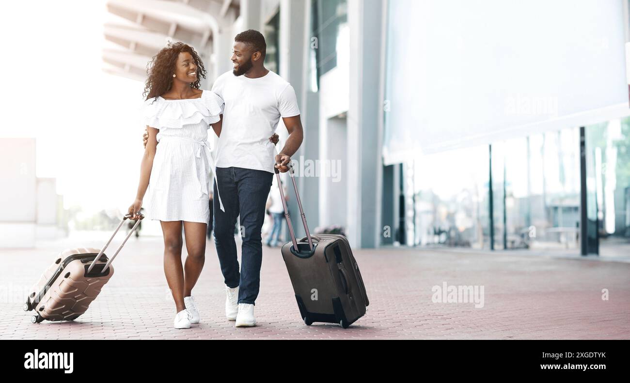Smiling Couple Walking With Luggage Next to Airport Terminal Stock ...
