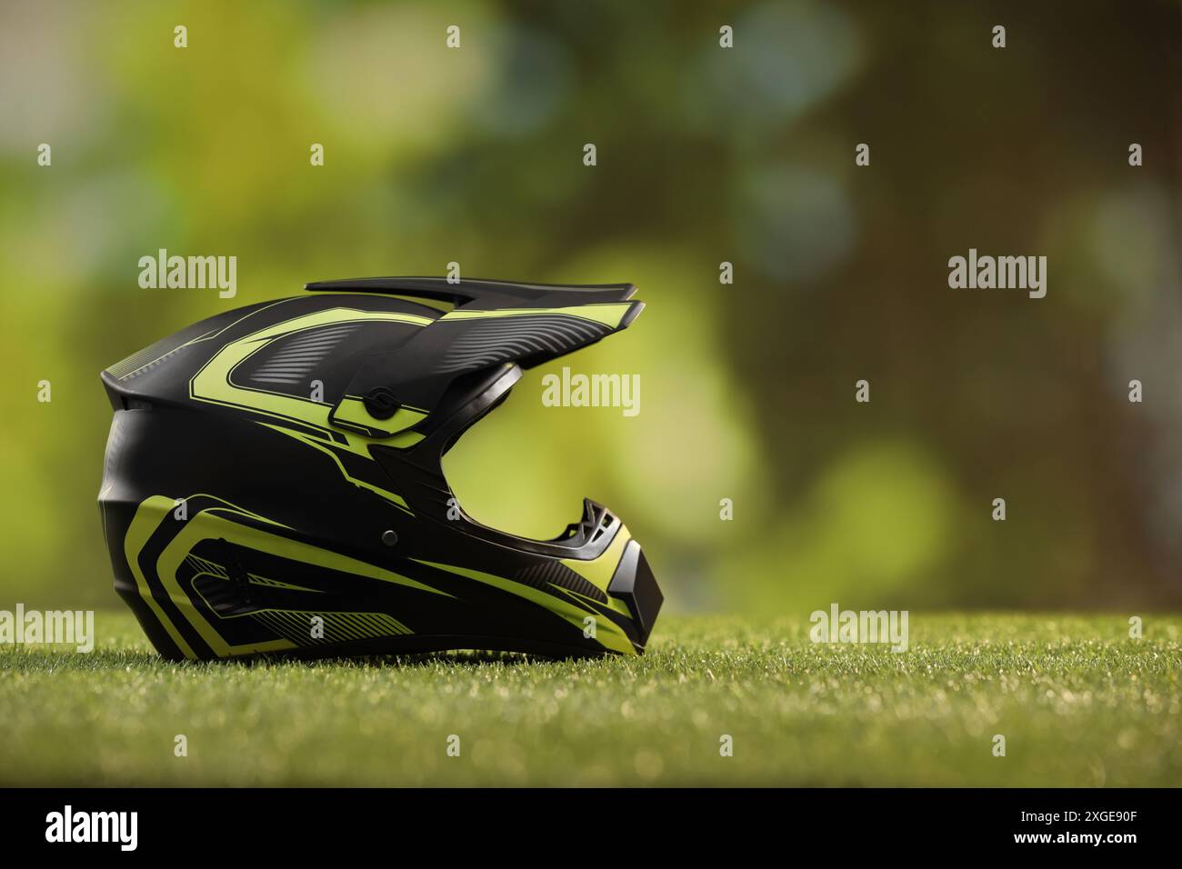 Modern motorcycle helmet with visor on green grass, space for text ...