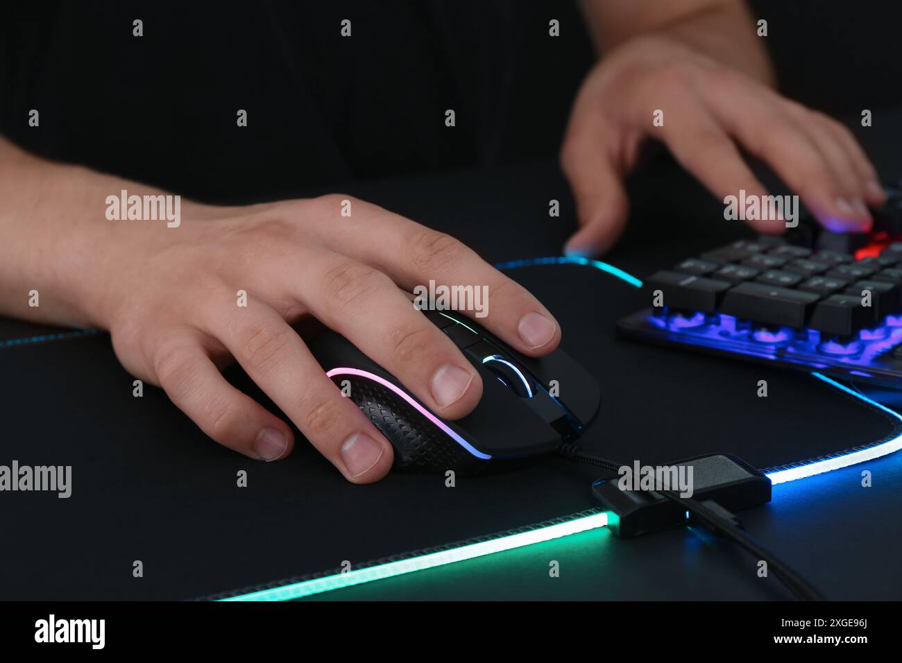 Gamer using modern wired computer mouse at black table, closeup Stock Photo