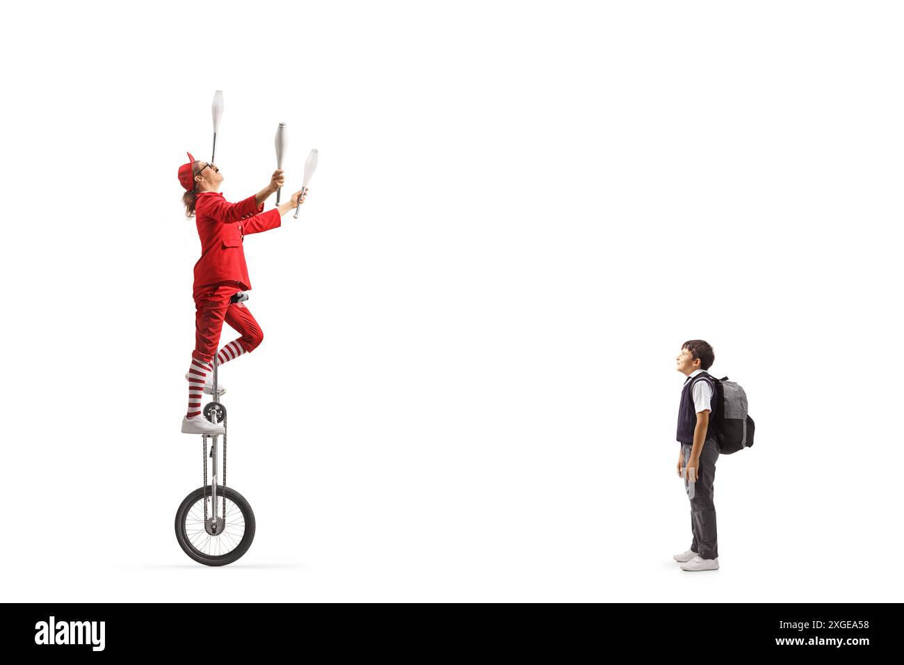 Schoolboy watching an acrobat riding a giraffe unicycle and juggling isolated on white background Stock Photo