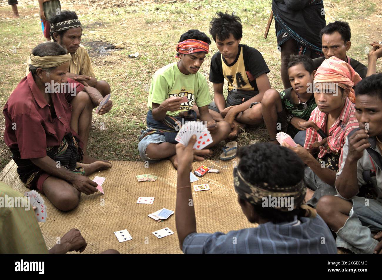 People play cards as they are taking a break from the preparation of a house construction and inauguration rituals in Ratenggaro, an indigenous village located in Umbu Ngedo, Kodi Bangedo, Southwest Sumba, East Nusa Tenggara, Indonesia. There are an estimated 476 million of indigenous people living in more than 90 countries, according to United Nations Development Programme (UNDP). Although they make up less than five percent of the world's population, they represent 15 percent of the poorest, according to the data. Stock Photo