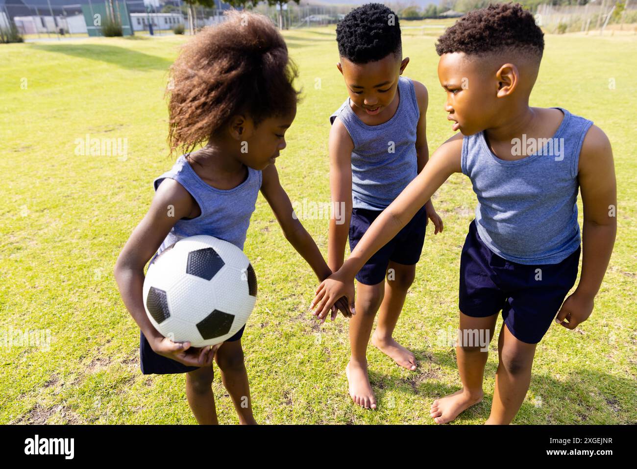 Happy african american schoolchildren playing football on field at ...