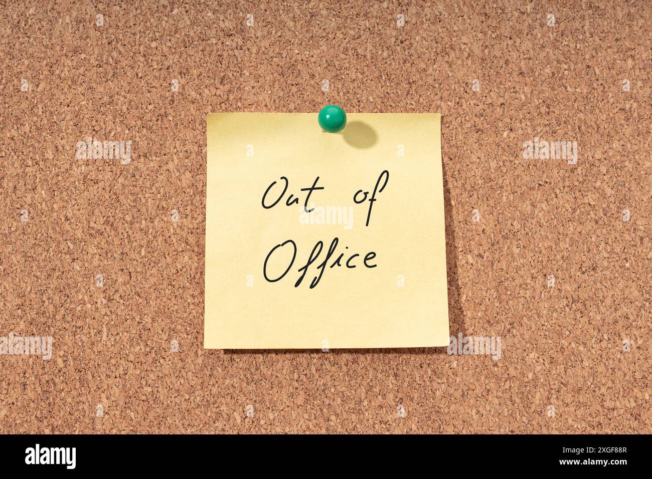 Yellow note with phrase out of office on cork board Stock Photo