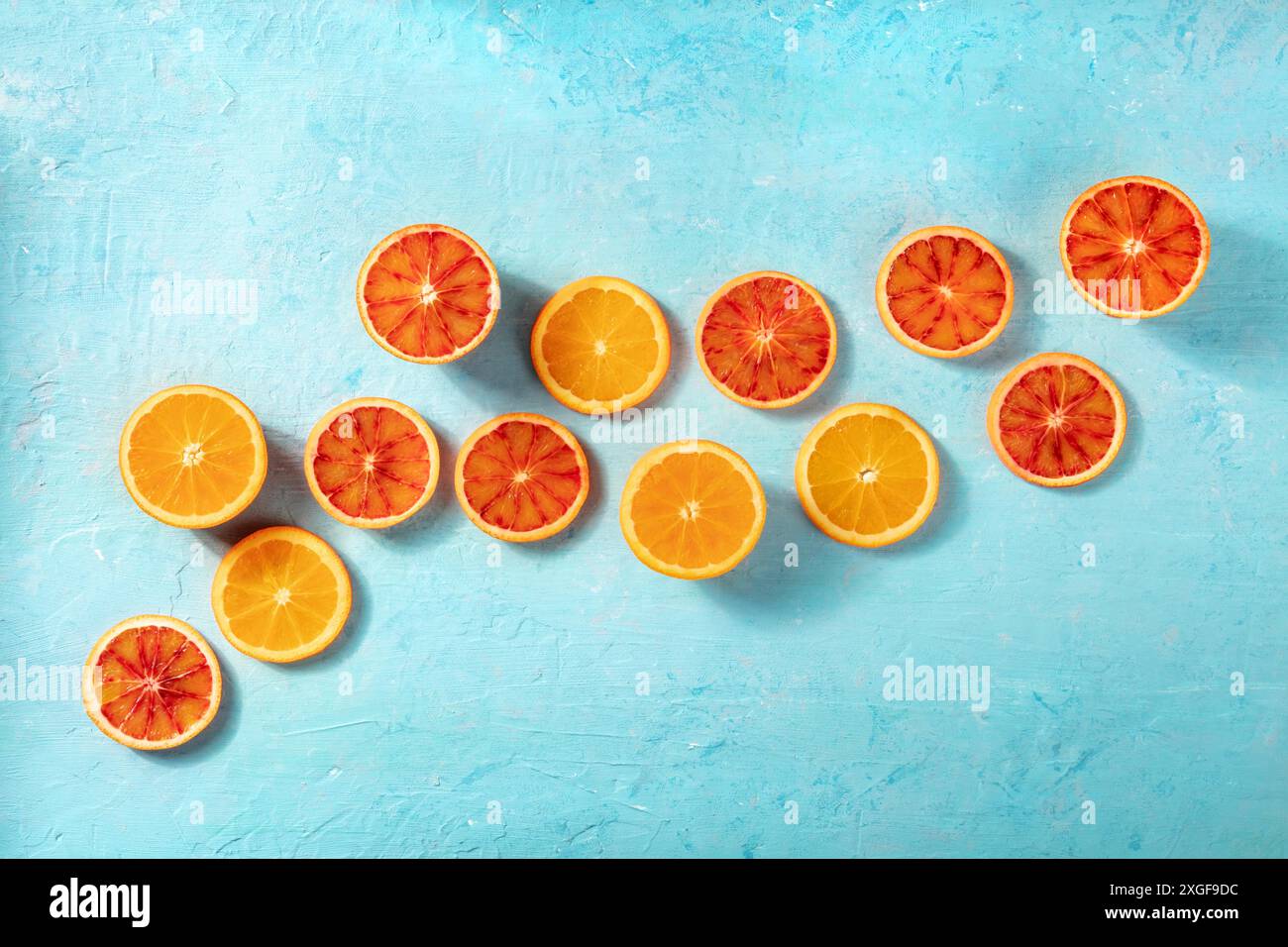 Blood oranges and regular oranges, overhead flat lay shot on a blue background with copy space. Summer banner Stock Photo
