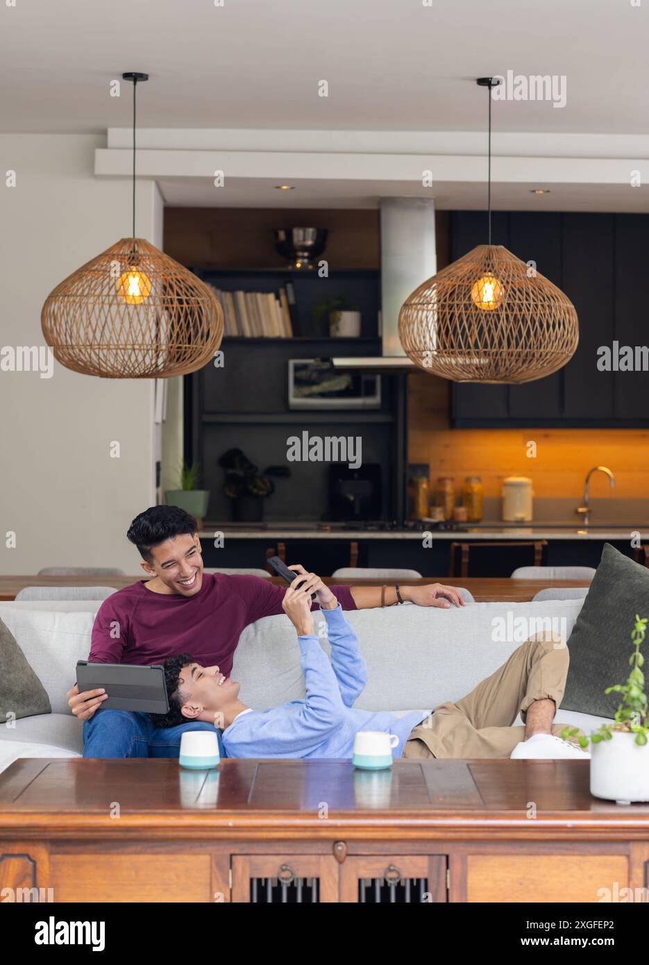 Relaxing at home, male gay couple laughing and using tablet on sofa Stock Photo