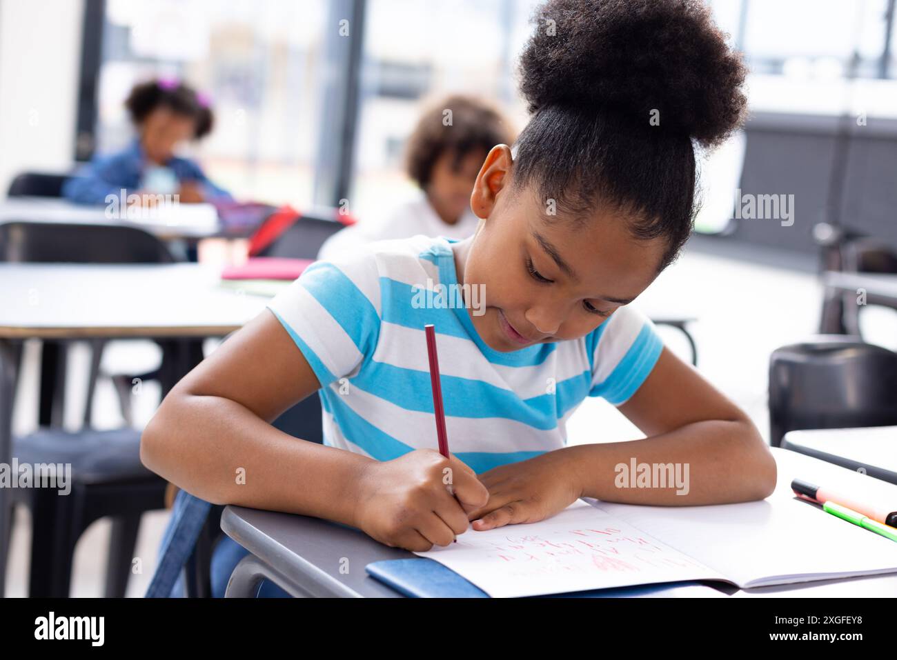 Happy african american schoolgirl sitting at desk in school classroom ...