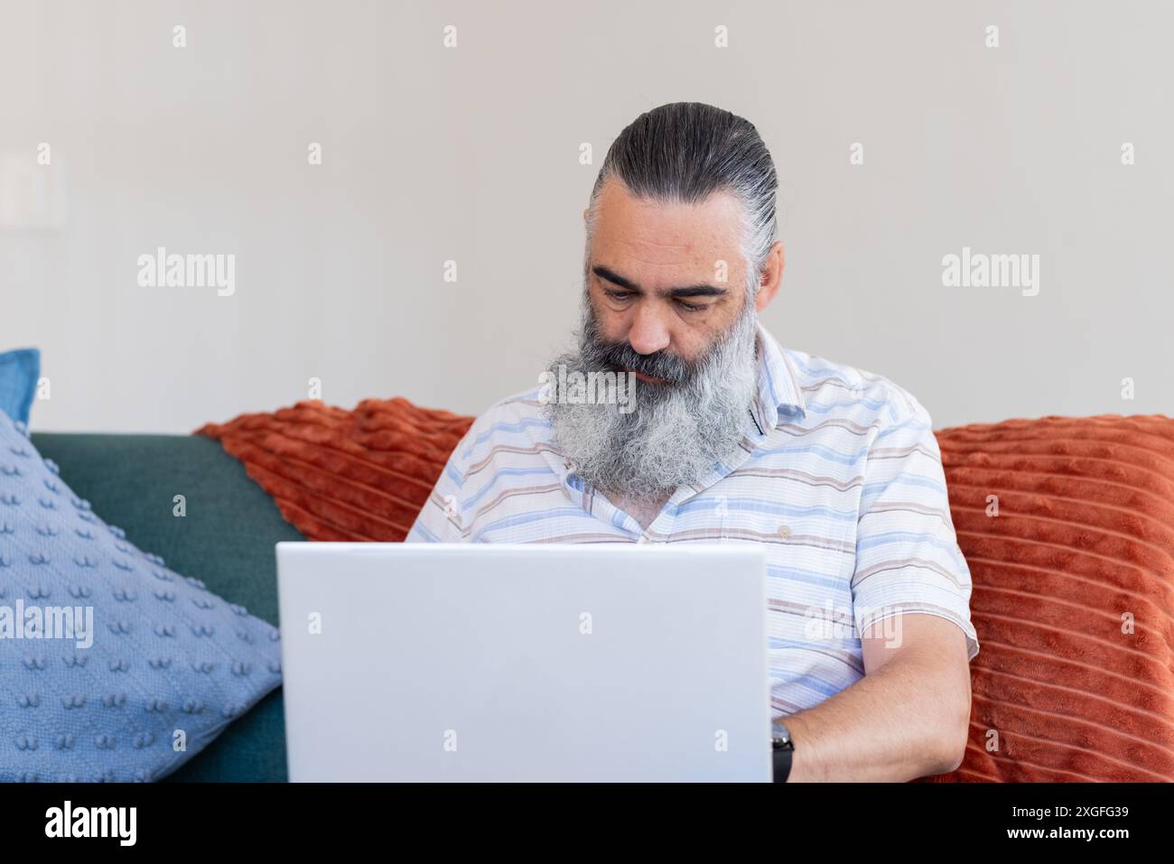 Working from home, senior man using laptop while sitting on couch Stock Photo