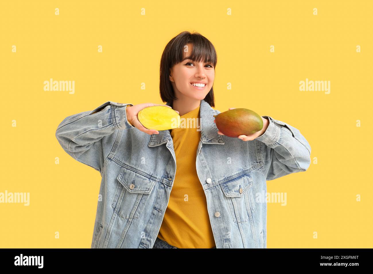 Beautiful young woman with ripe mangoes on yellow background Stock ...
