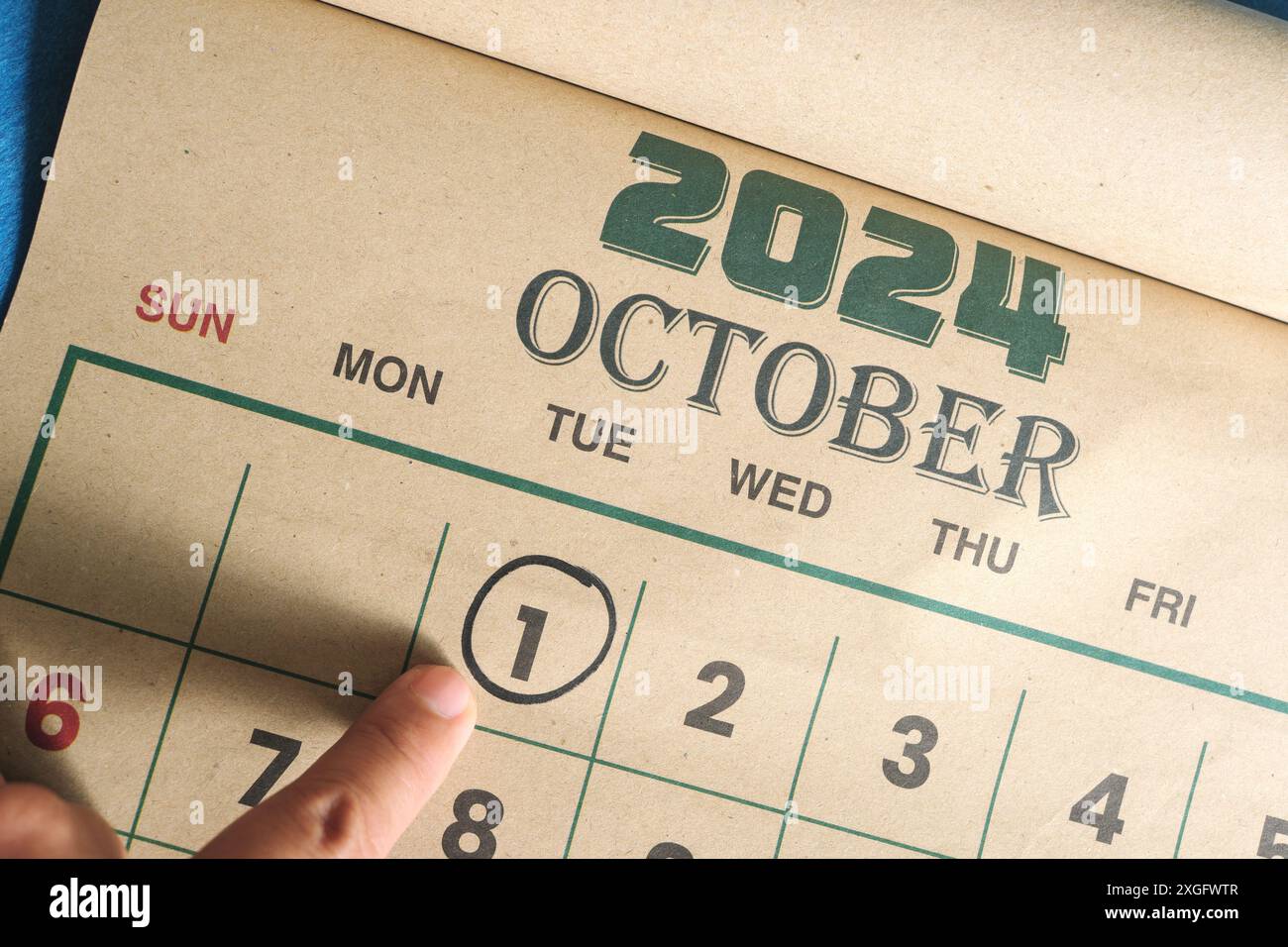 Hand pointing on October 1 2024 date on calendar flat lay in blue background. First day of the month reminder. Stock Photo