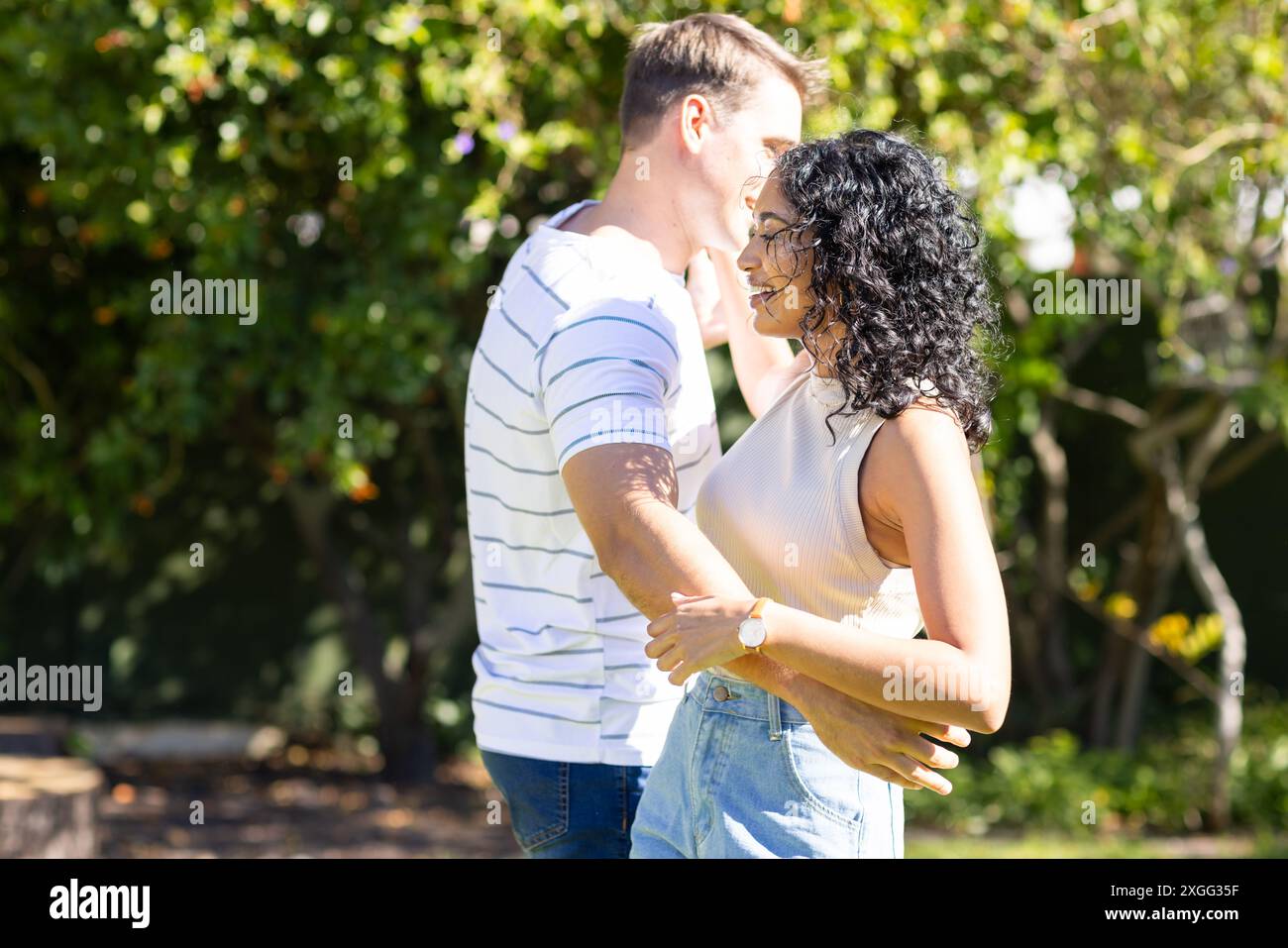 Young couple dancing together outdoors, enjoying sunny day in park Stock Photo