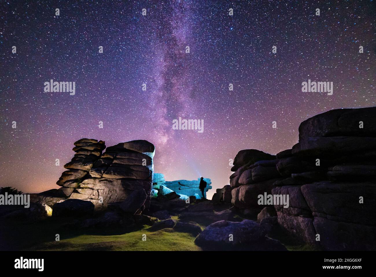 A figure beneath the Milky Way in the night sky over Dartmoor National Park, Devon, UK Stock Photo