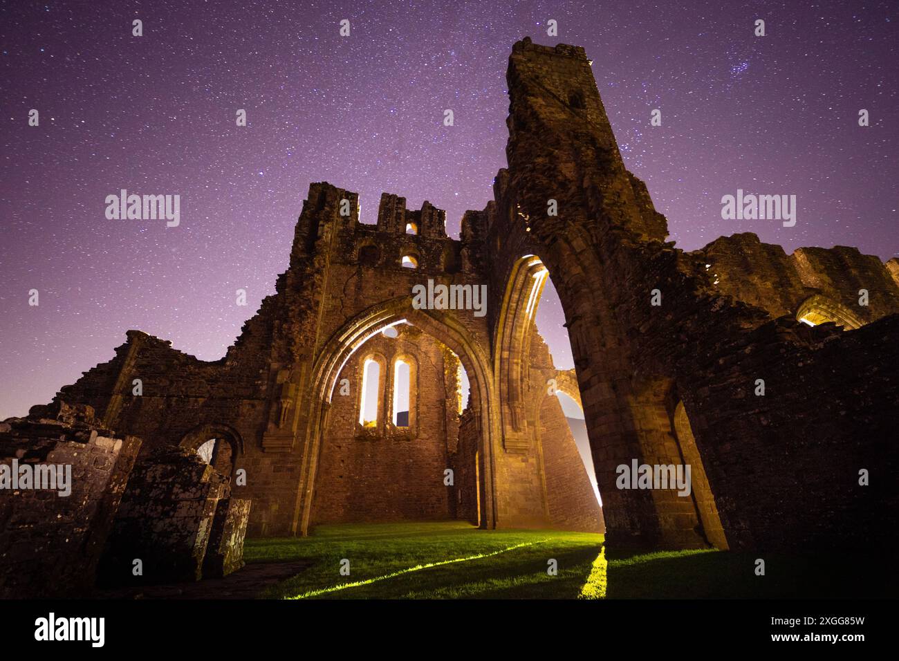 A starry night sky over the light painted ruins of Llanthony Priory in the Vale of Ewyas, Wales, UK Stock Photo