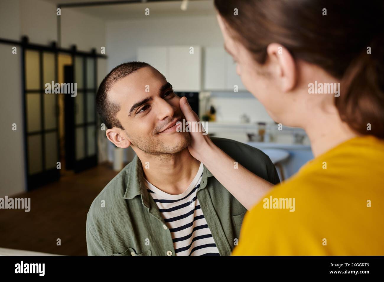 A young gay couple enjoys a moment of intimacy in a modern apartment ...