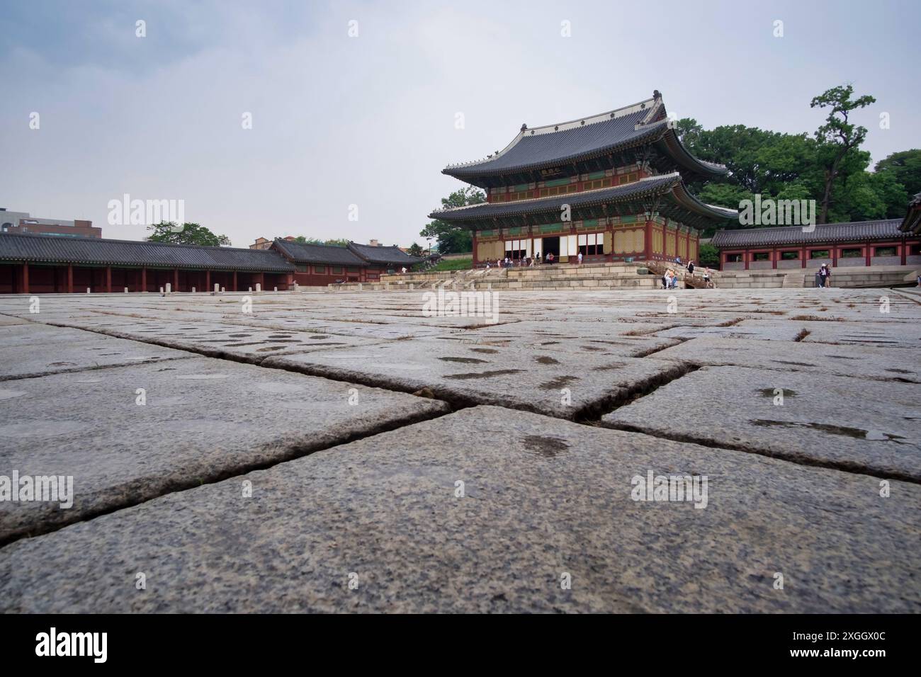 Ancient Korean palace courtyard with stone pavement and traditional buildings, modern city visible in background Stock Photo