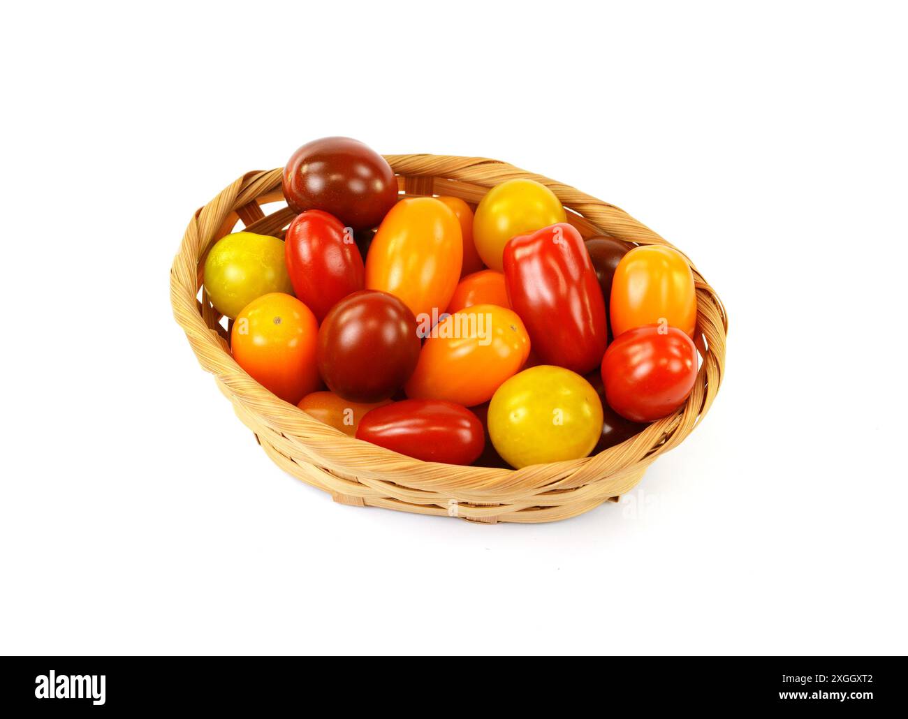Different sorts of tomatoes in a woven basket isolated on white ...