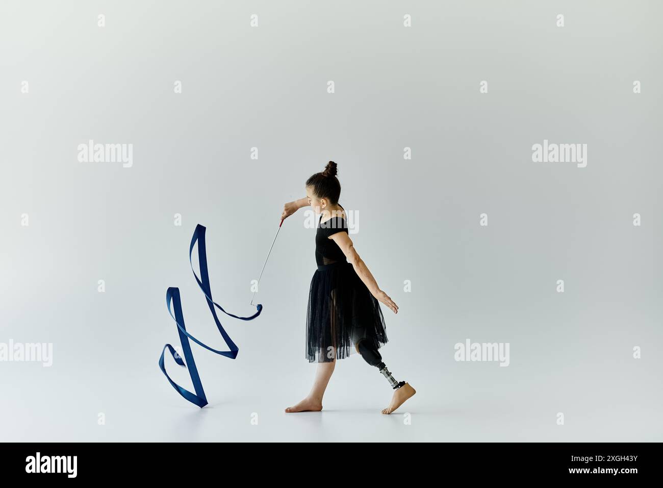 A young girl with a prosthetic leg performs gymnastics with a blue ...