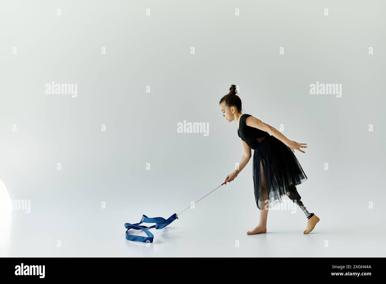 A young girl with a prosthetic leg performs a graceful ribbon routine ...