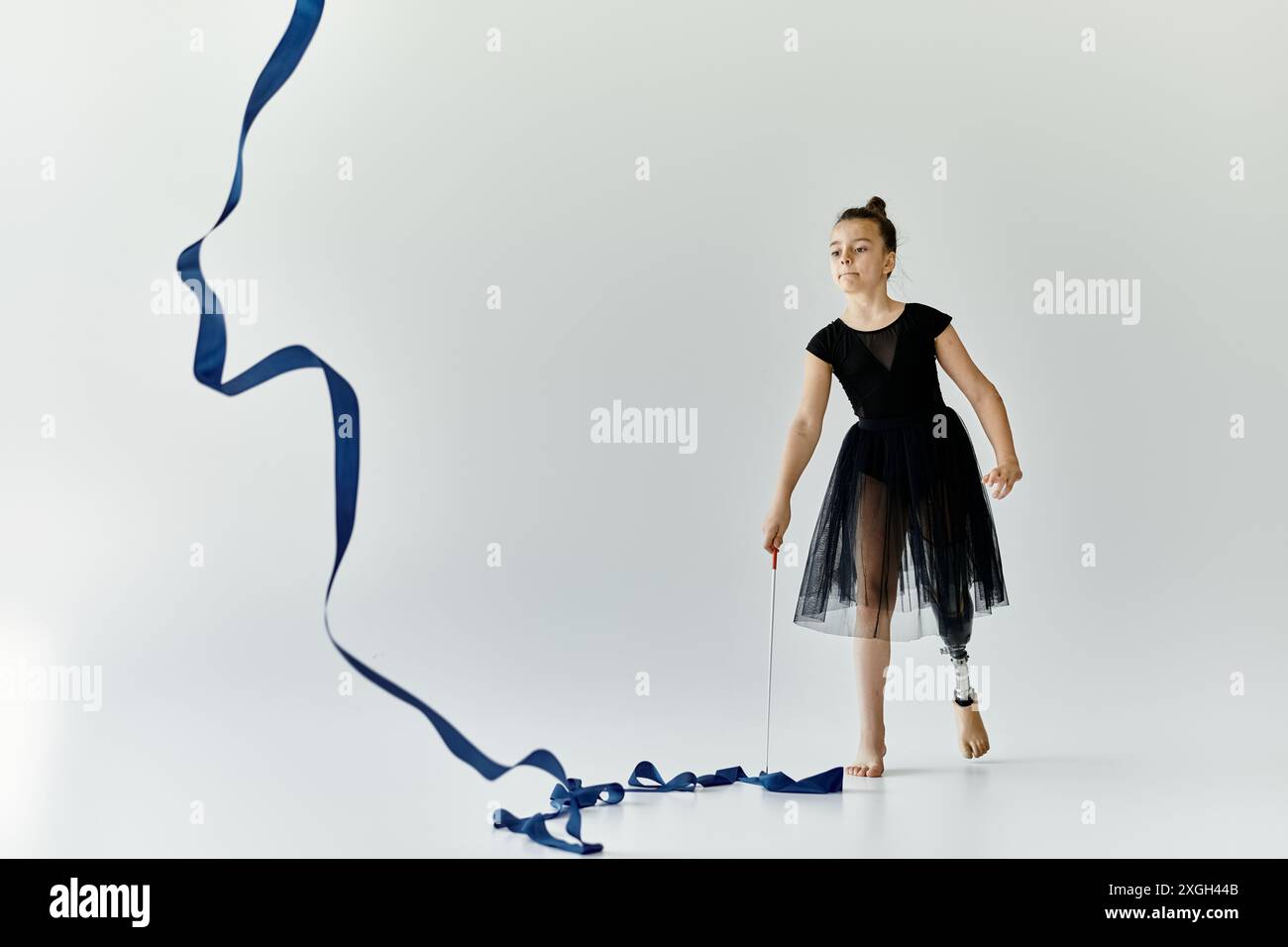A young girl with a prosthetic leg gracefully performs a ribbon routine ...
