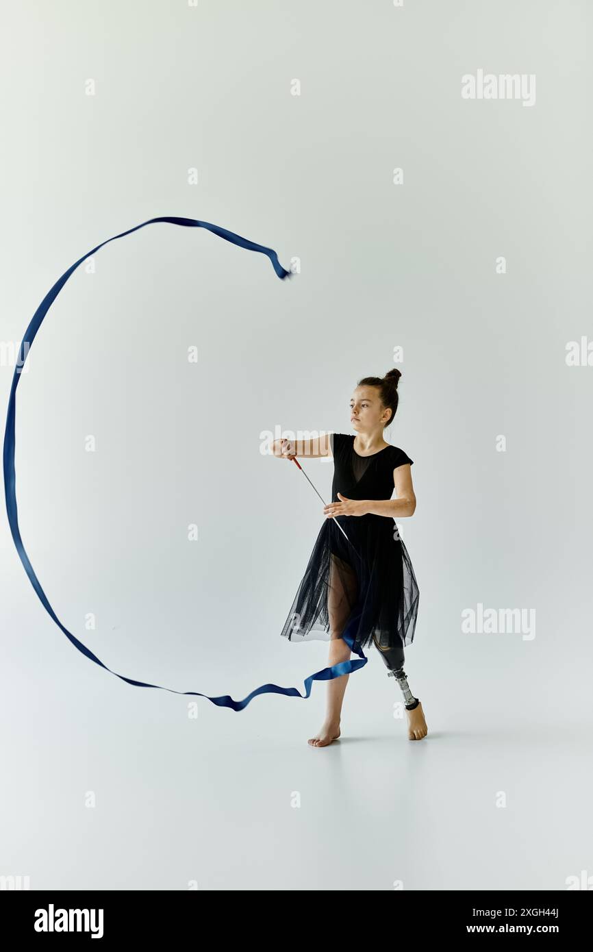 A young gymnast with a prosthetic leg gracefully manipulates a ribbon ...