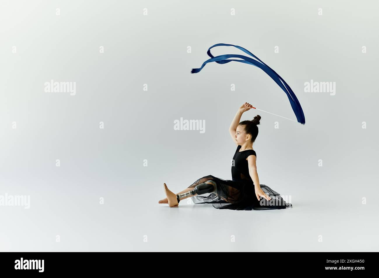 A young girl with a prosthetic leg practices her gymnastics routine ...