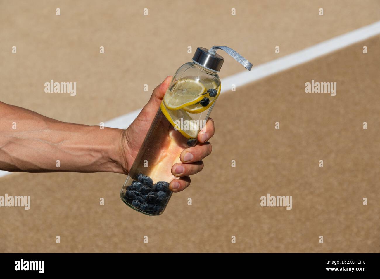 Reusable sport glass bottle with lemon and berry or isotonic in athlete ...