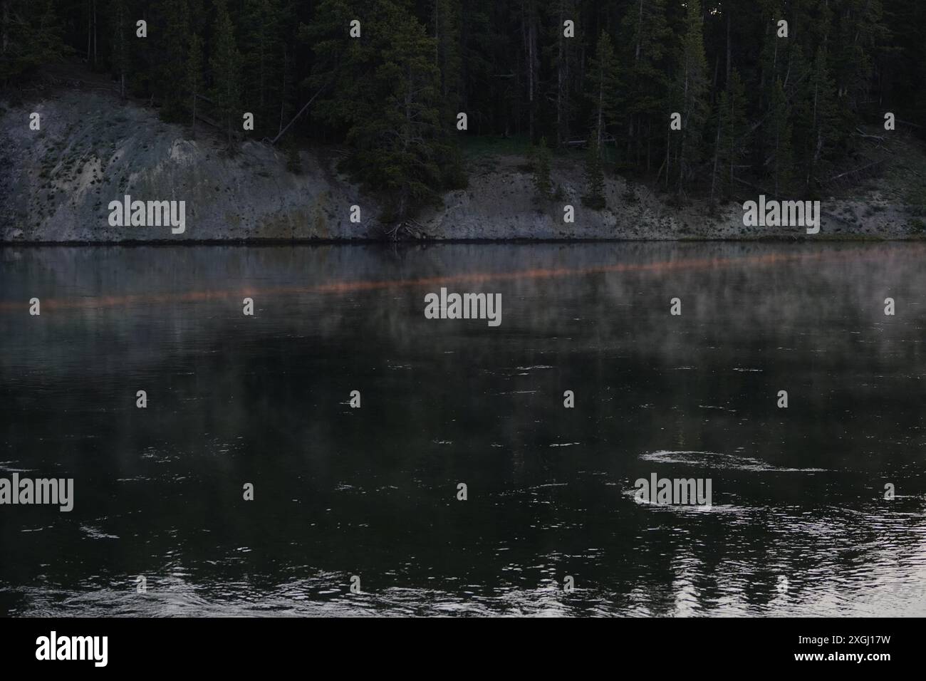 Orange Ray of Early Morning Sunlight Across Steaming Yellowstone River Stock Photo