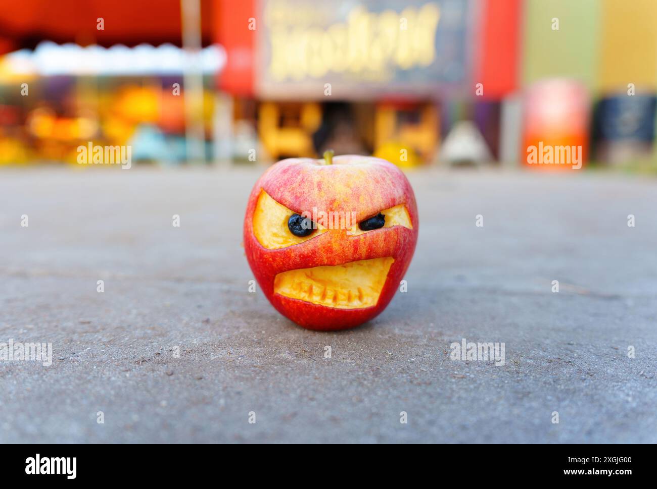 Red apple with a carved angry face, featuring eyes and a mouth, set ...