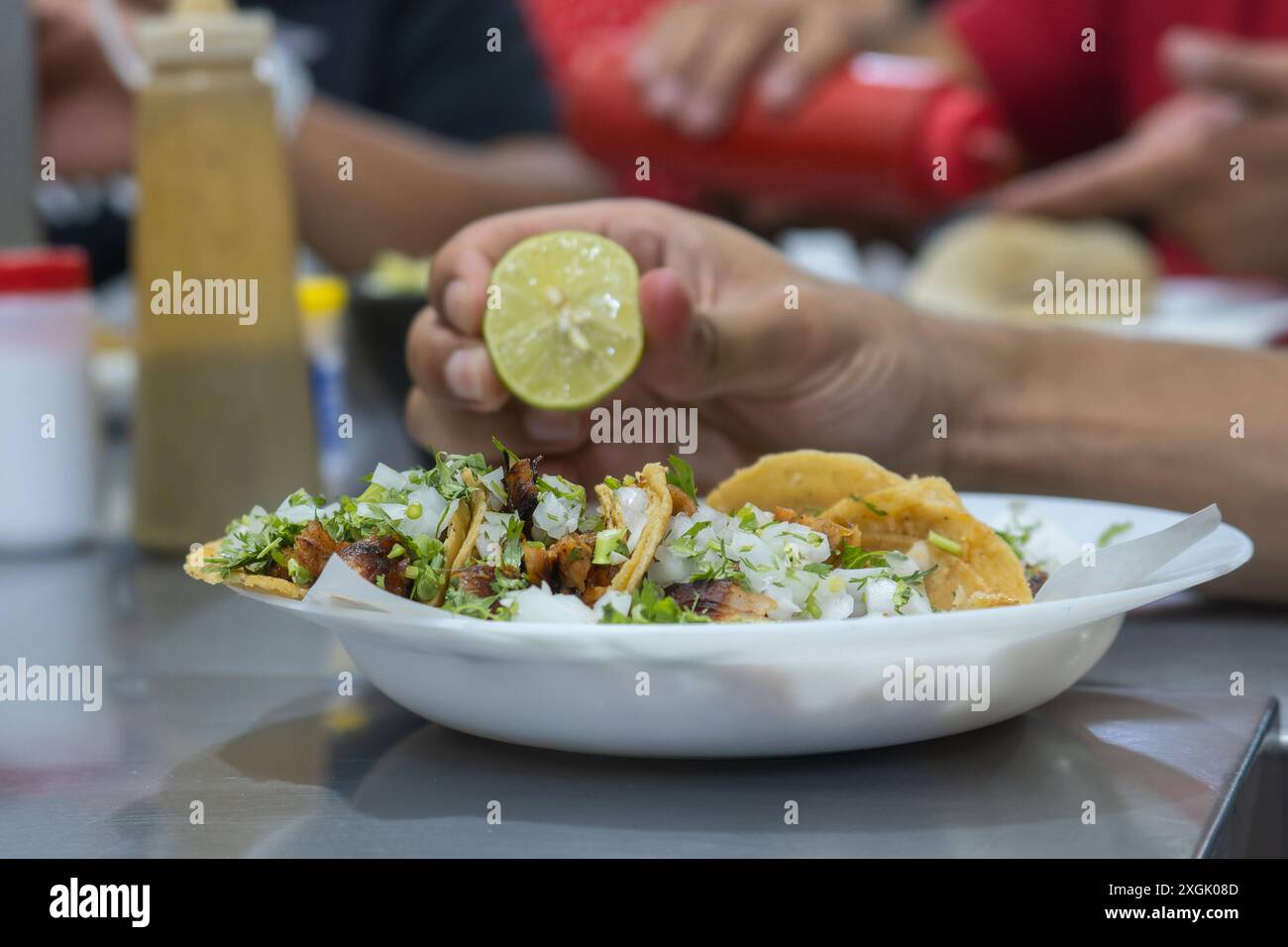 Close-up shot of delicious tacos brimming with fresh ingredients like onions and cilantro, garnished with a lime squeeze. Perfect for illustrating Mex Stock Photo