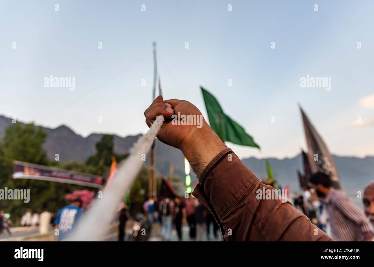 A Kashmiri Shia Muslim man pulls the rope of a tall religious flag ...
