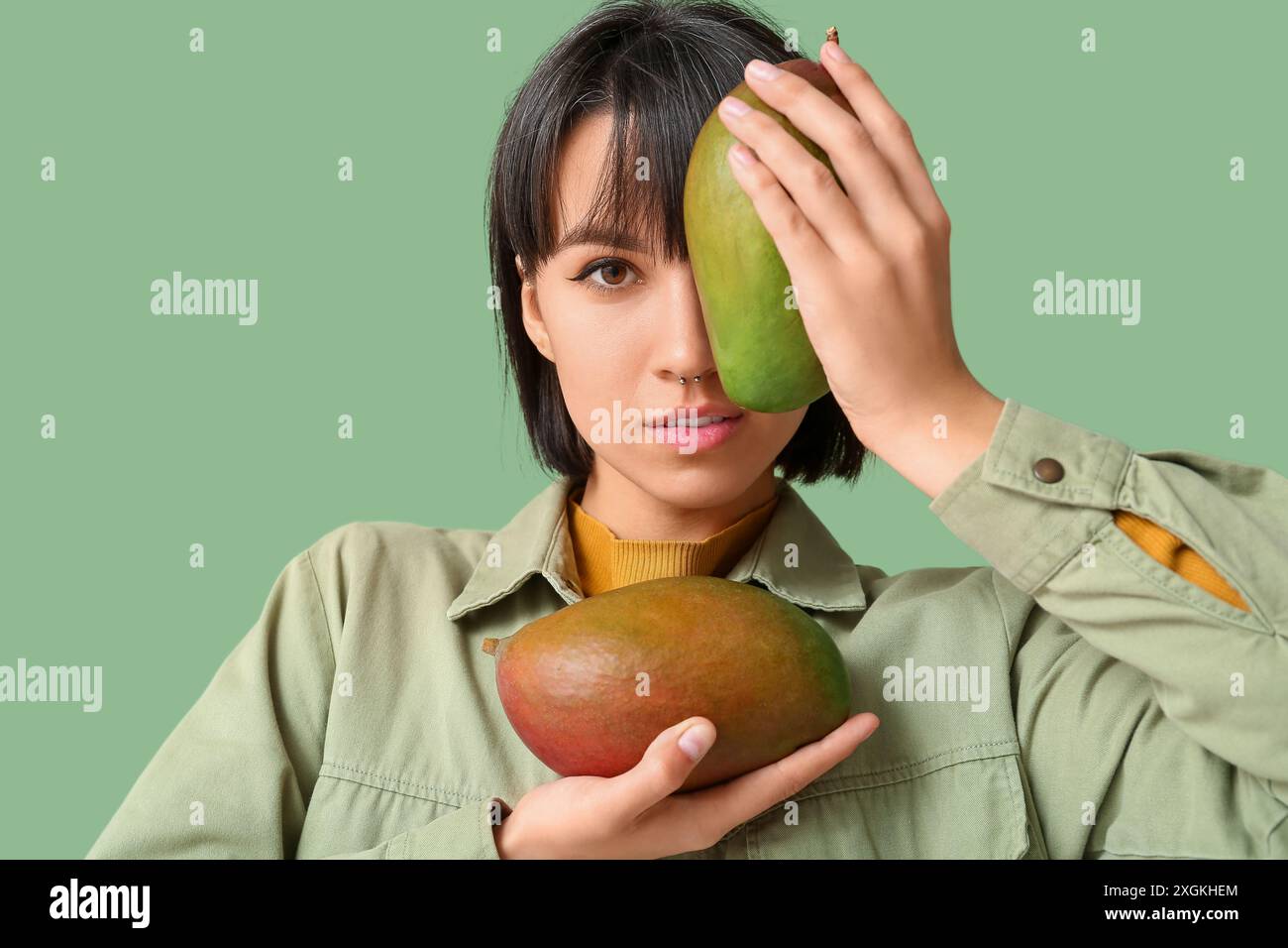 Beautiful young woman with ripe mangoes on green background Stock Photo ...
