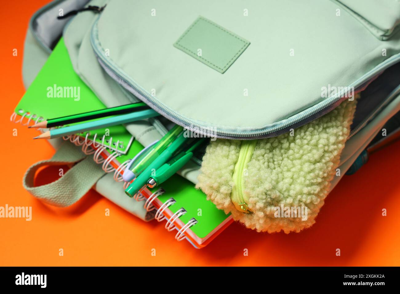 Backpack with school supplies on orange background Stock Photo
