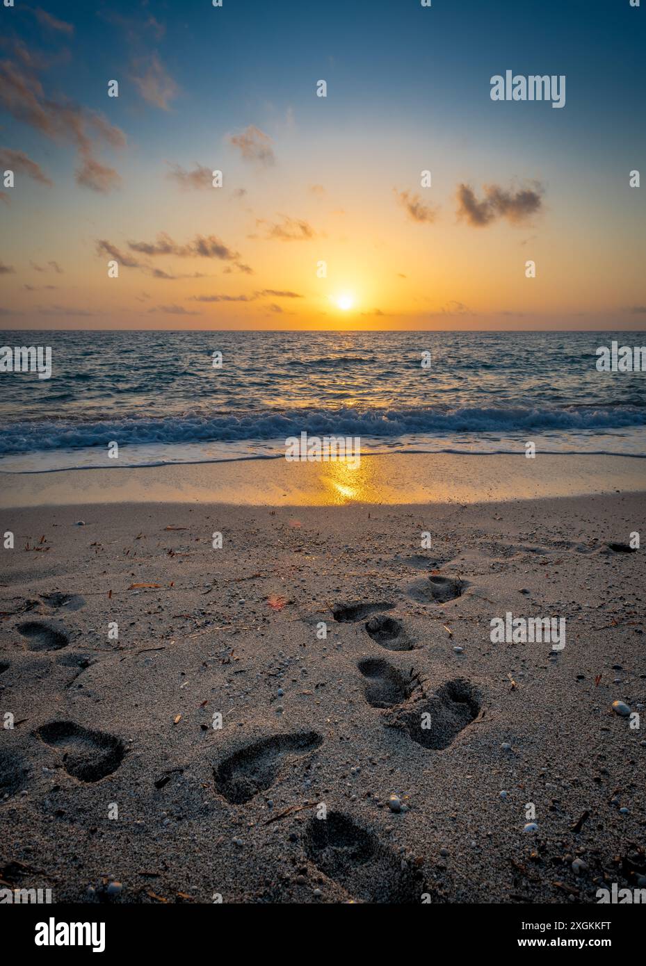 Beach sunset with footprints on the sandy beach Stock Photo - Alamy