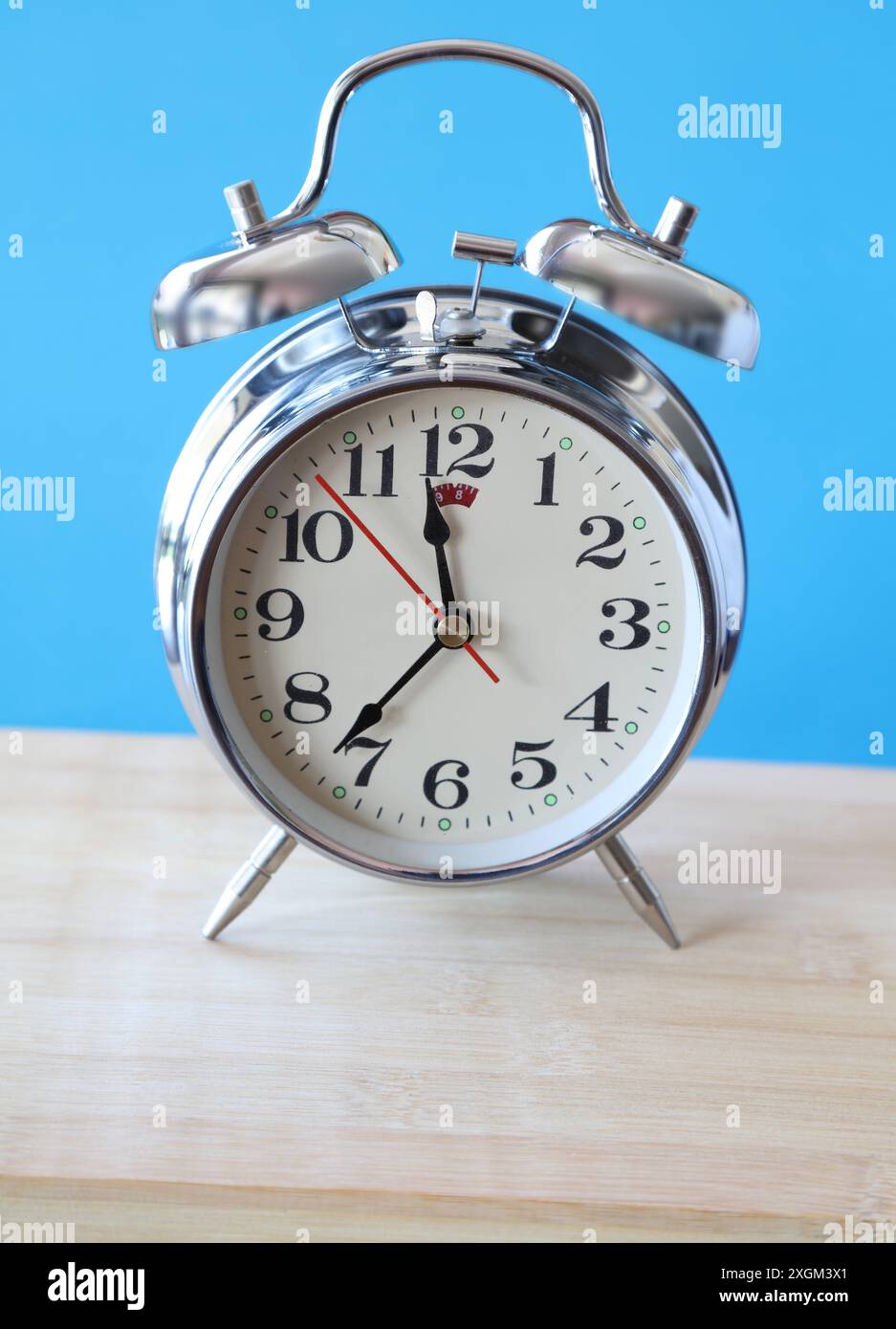 Retro alarm clock on table in front of blue background Stock Photo