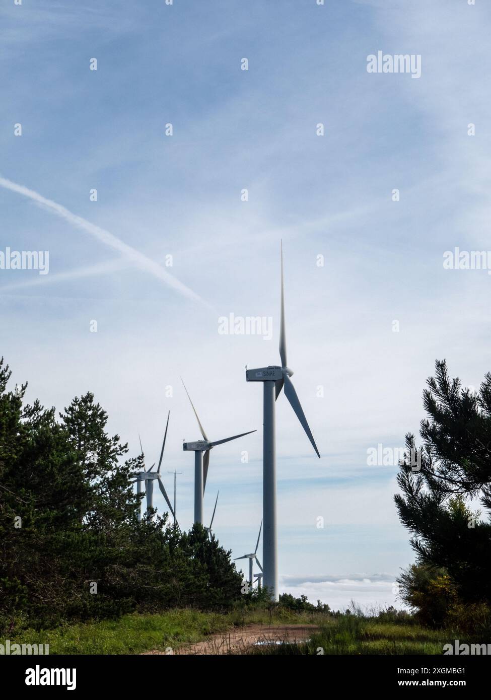Wind turbines stand tall against a bright blue sky with white clouds ...