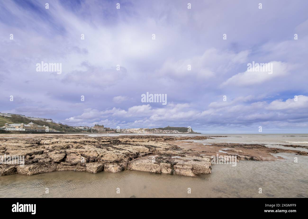 Looking across the South Bay at Scarborough on the North Yorkshire Coast. Low tide has exposed the rock pool and in the distance is the headland with Stock Photo