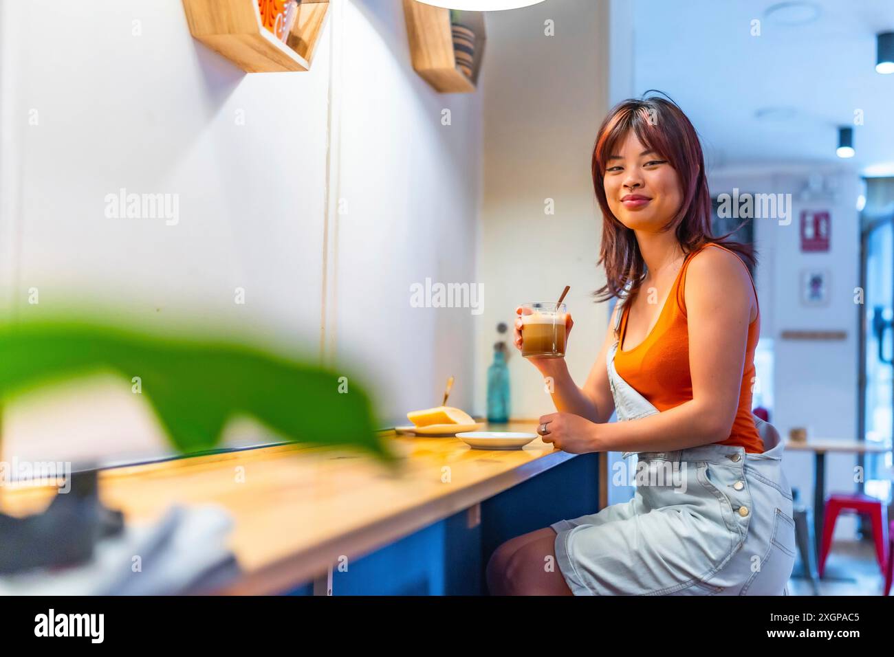 Portrait with copy space of a smiling asian youthful woman drinking coffee in a cafeteria Stock Photo