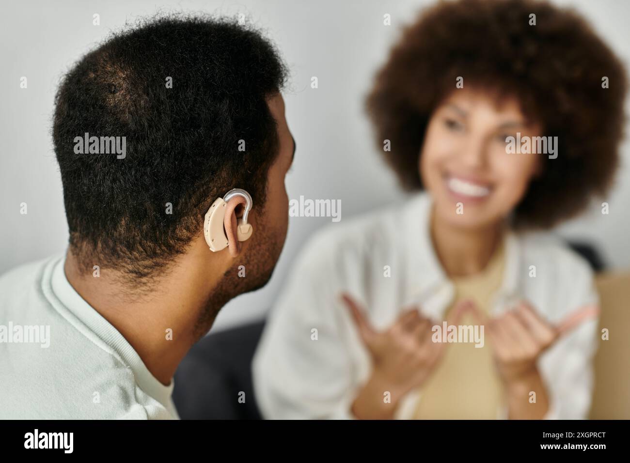 A young African American couple sits at home, communicating in sign language. Stock Photo