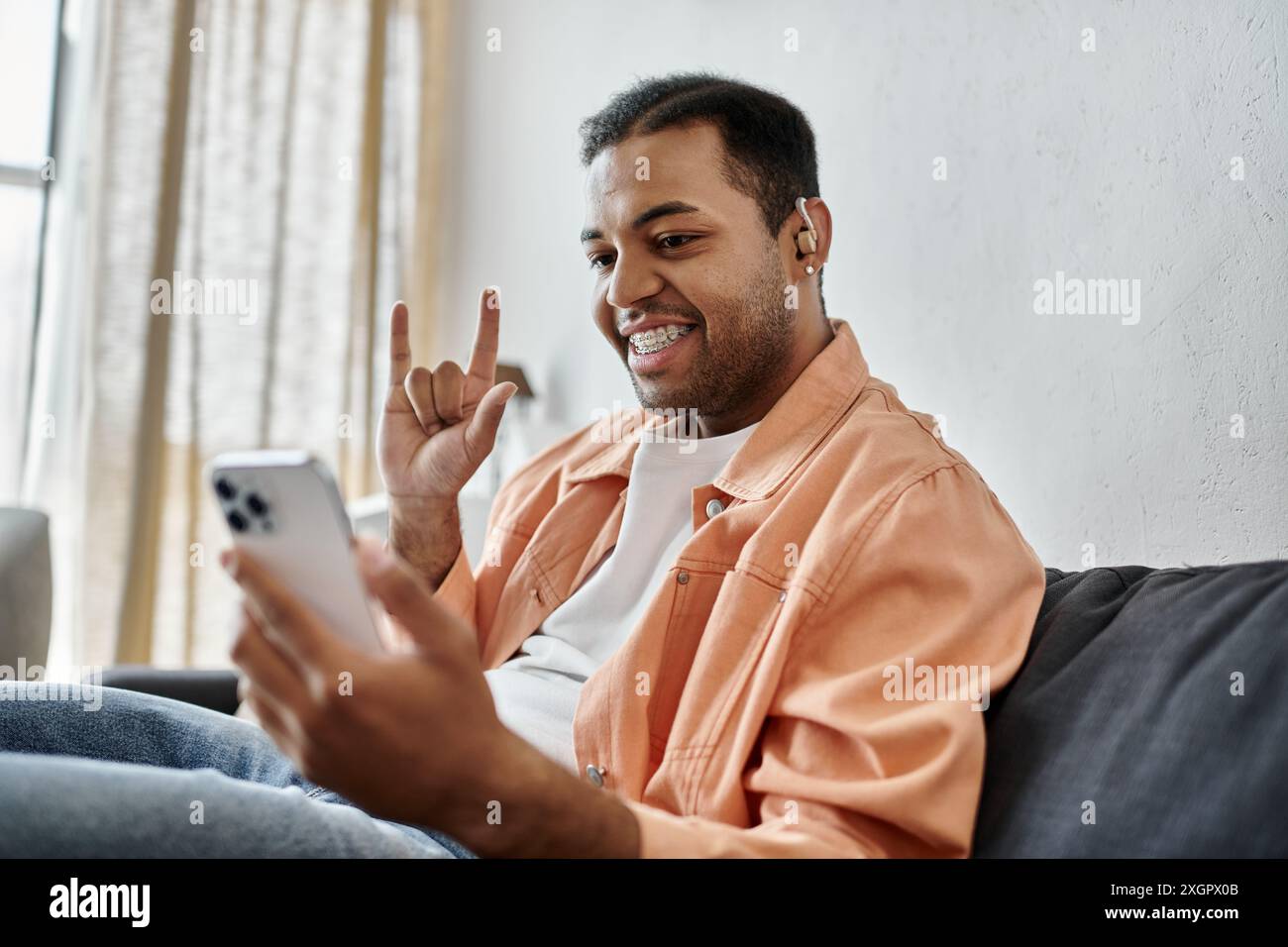 A man smiles as he signs while using his smartphone. Stock Photo