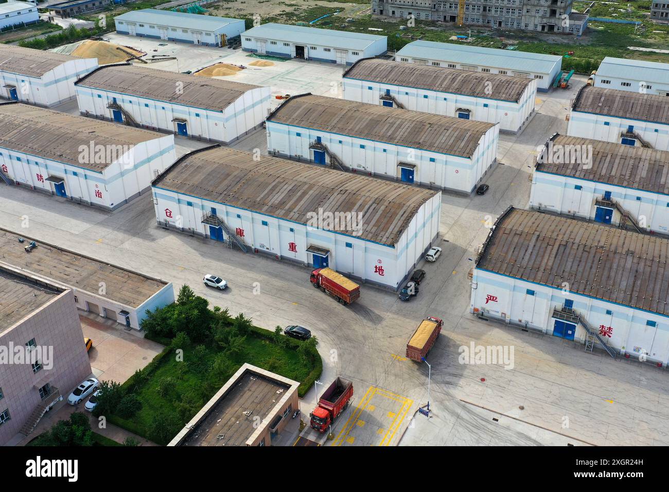 Qitai. 9th July, 2024. A drone photo taken on July 9, 2024 shows storehouses of a grain and oil company in Qitai County, Changji Hui Autonomous Prefecture, northwest China's Xinjiang Uygur Autonomous Region. In recent days, Qitai County, a major wheat production area in northwest China's Xinjiang, greets its harvest season. Credit: Ding Lei/Xinhua/Alamy Live News Stock Photo