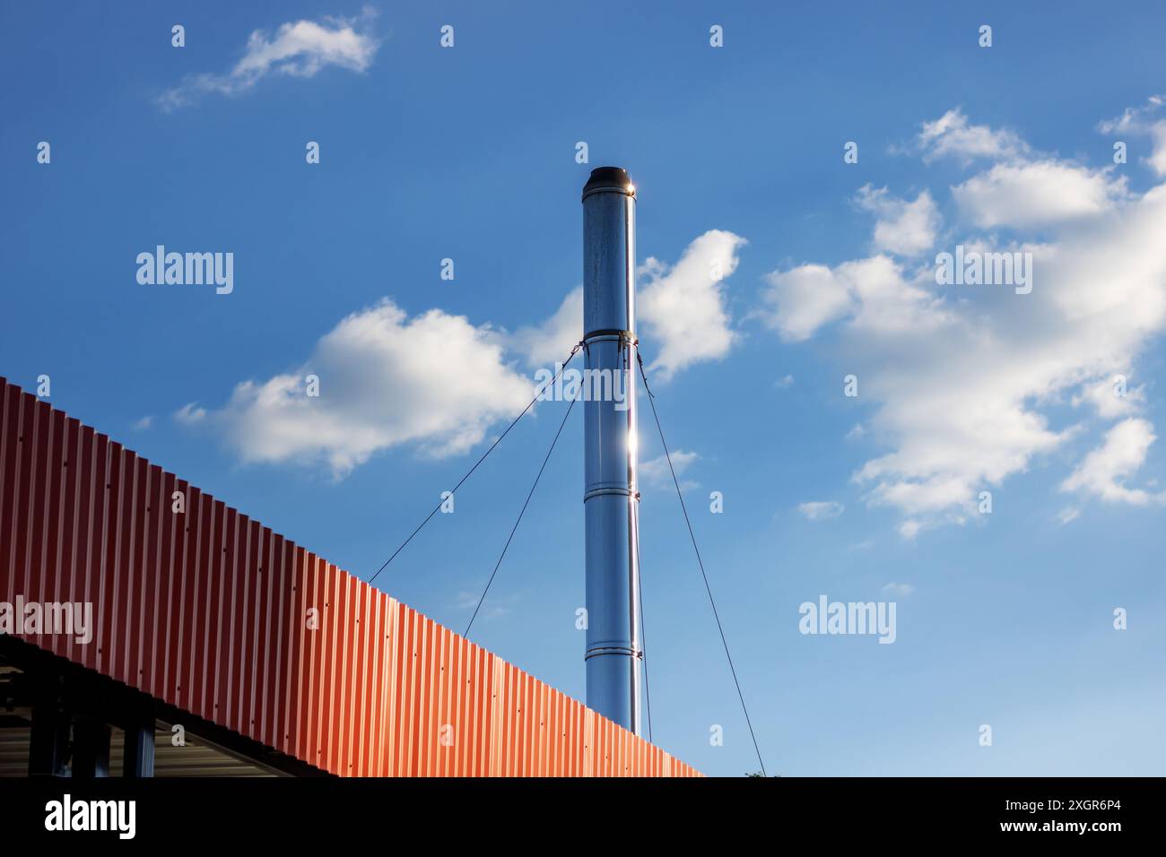 A very tall brick chimney stands out against a clear blue sky dotted ...