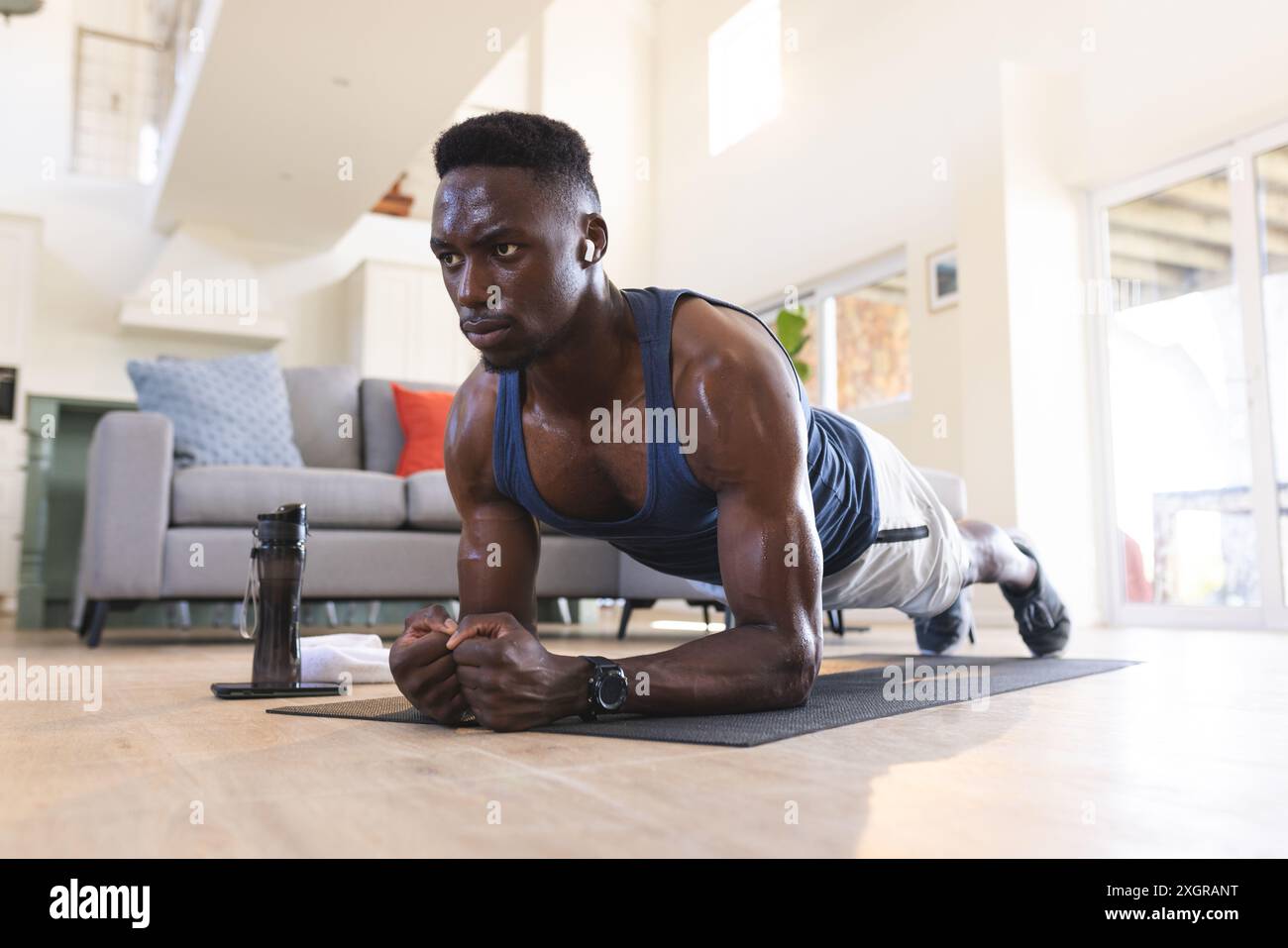 Unalt Fit african american man exercising at home, lying on floor in plank ...