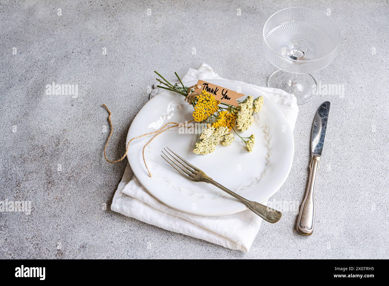 A rustic table setting featuring a white plate with fresh achillea ...