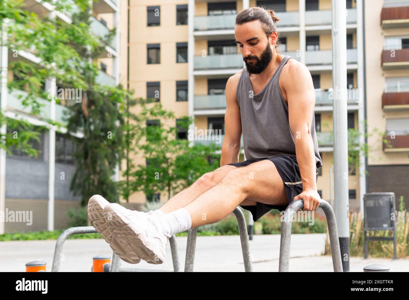 A focused young man with a beard is seen performing leg exercises on ...