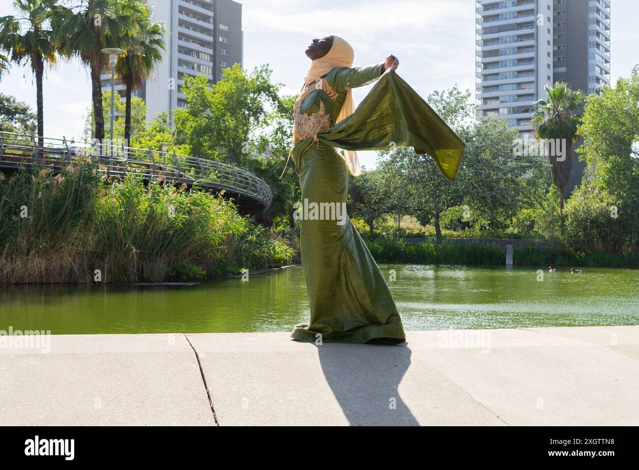 An elegantly dressed woman in a flowing green dress and turban poses ...