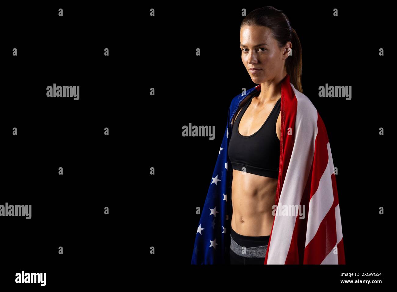 Young Caucasian female athlete draped in an American flag stands ...